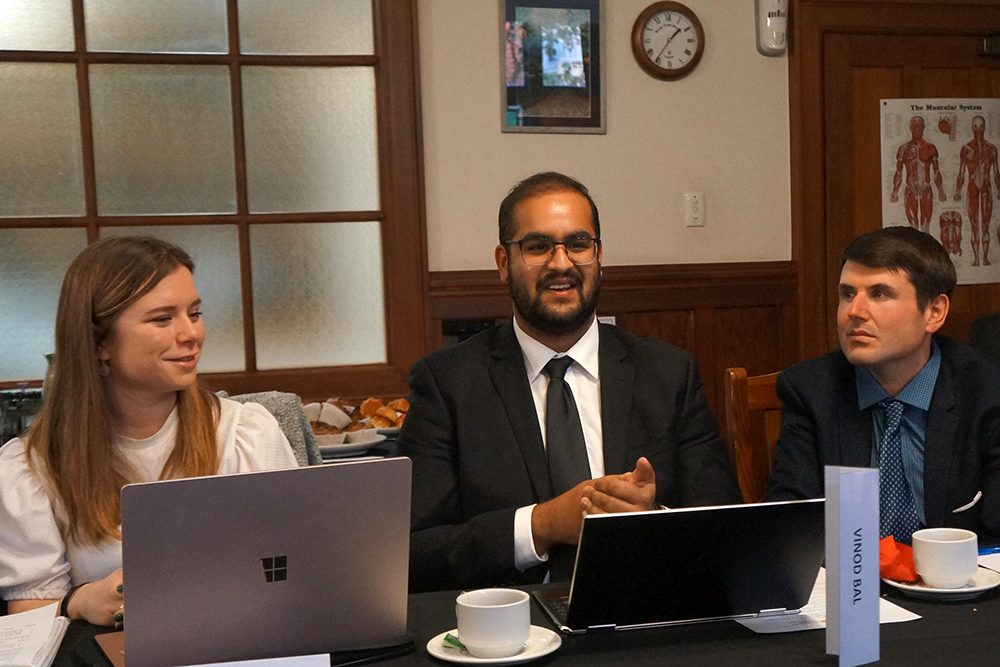Vinod sitting at a table addressing a group