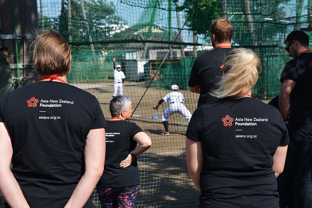 A group of teachers watching kids playing baseball