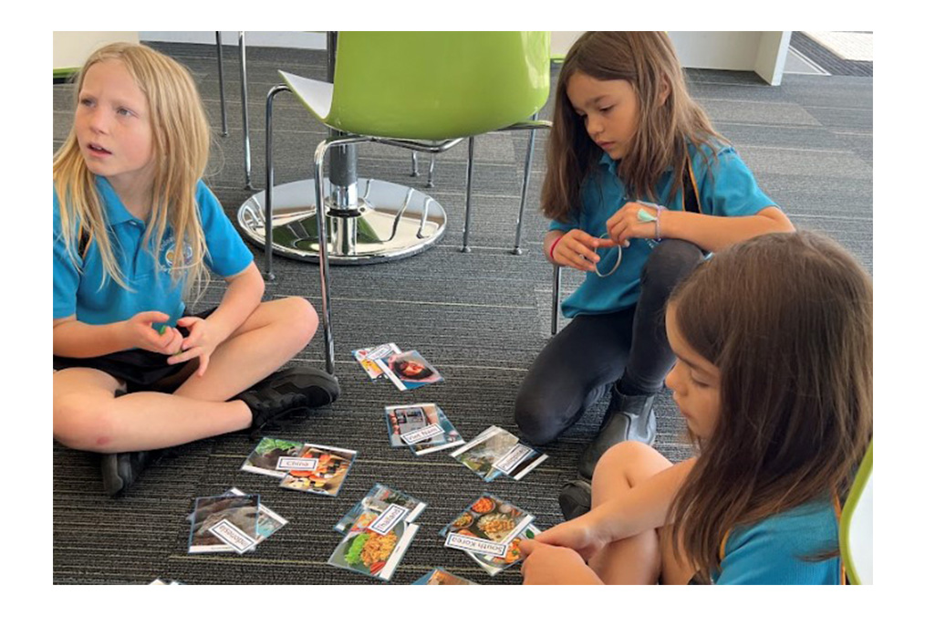 Three students sitting on the ground sorting photos