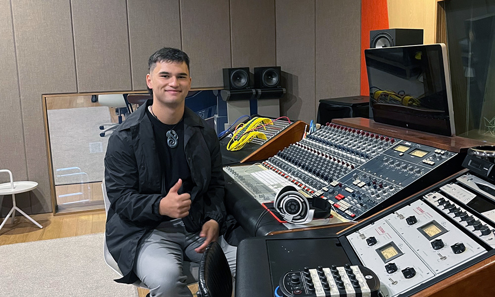 Brigham sitting at a mixing desk giving the thumbs up