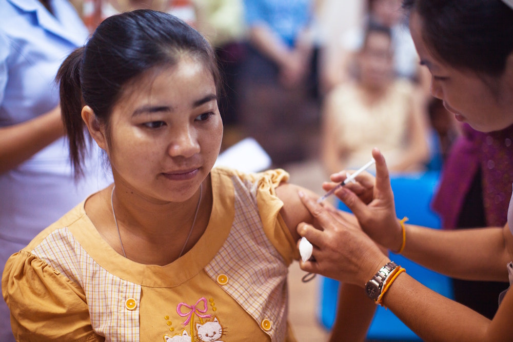 A woman administering a jab into the arm of another woman