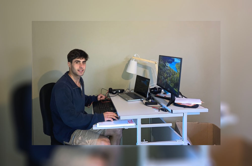 Cooper sitting in front of his computer at his desk
