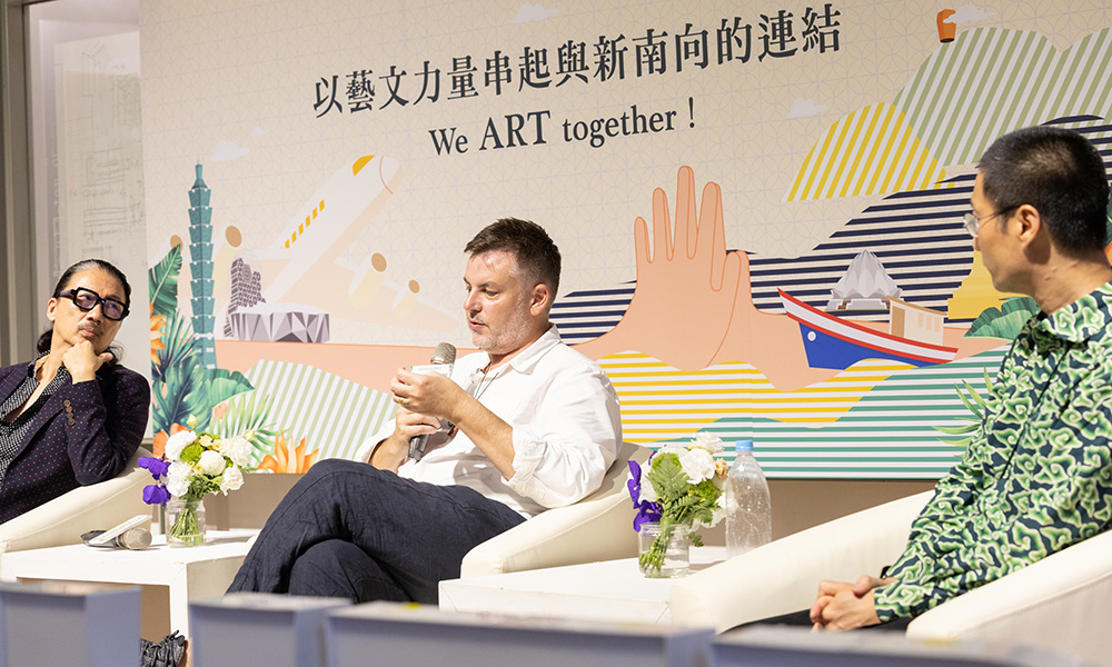Director Arts Craig Cooper speaking on a panel with the words 'We Art Together on the wall behind him