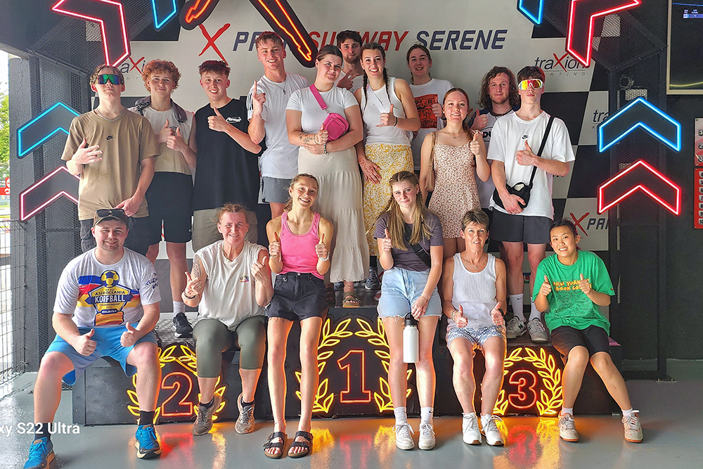 The team in their street clothes posing for a photo at the entrance to the go-cart track building