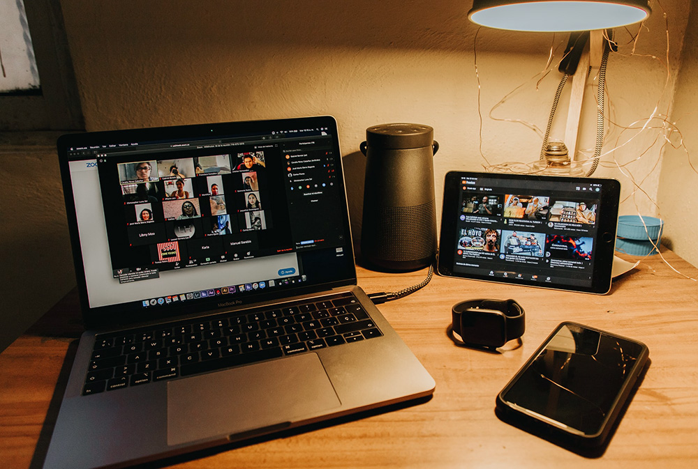 A laptop with a zoom meeting on the screen and the faces of a dozen people