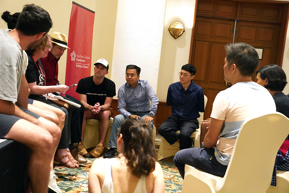 A group of ten people sitting on chairs in a circle chatting