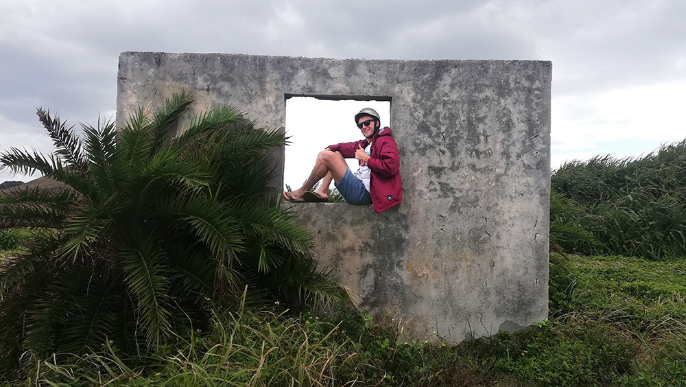 Tim sitting on a concrete wall of a ruined building