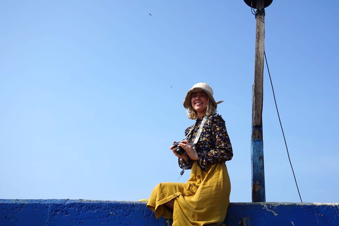 Katie sitting on a wall holding a camera