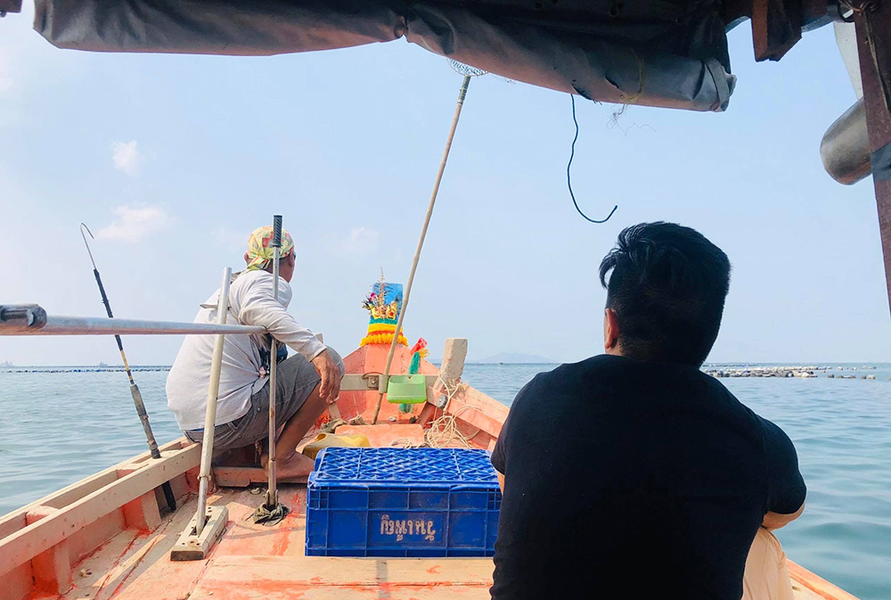 Mikhael sitting in a small wooden longboat commonly seen in Thailand