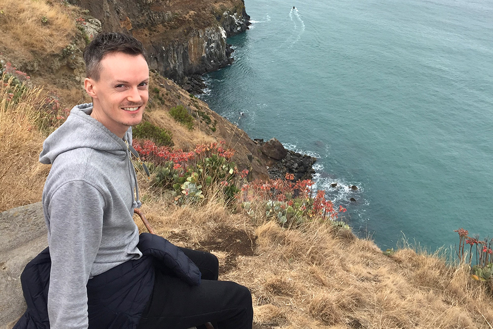 Marcus Coll sitting above a cliff overlooking the sea