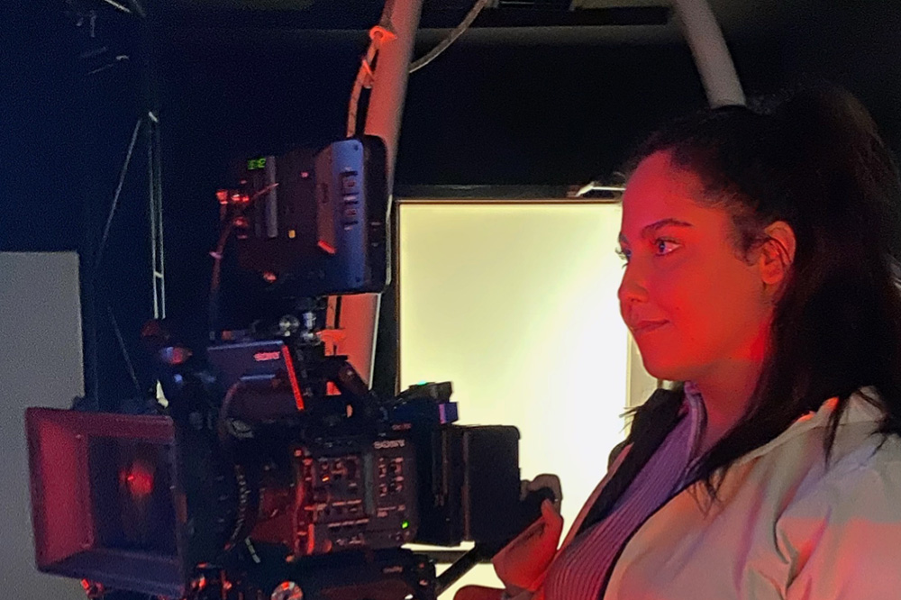 Melika lit by red light, looking through a camera lens
