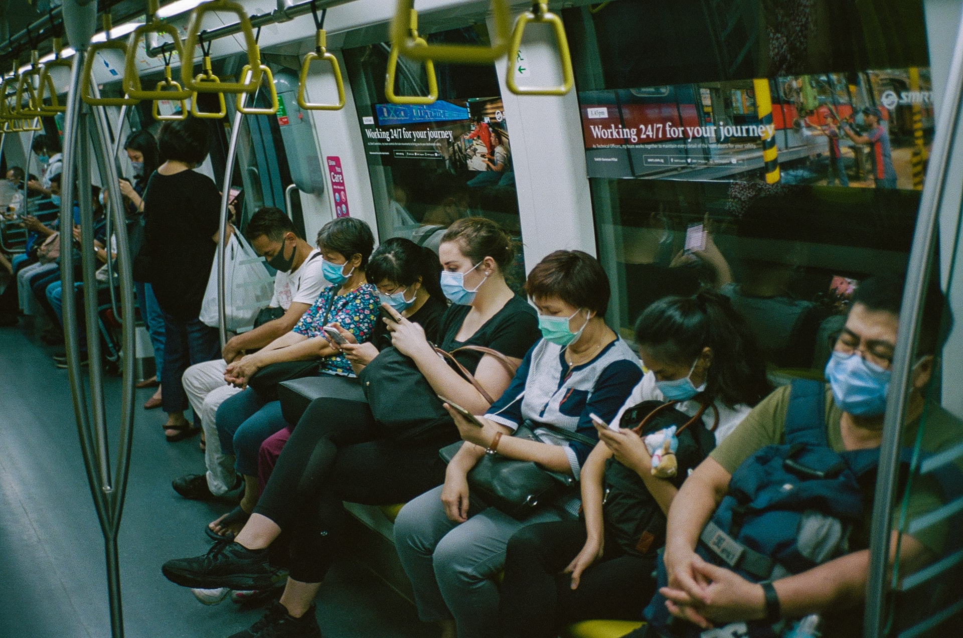 People sitting on a train wearing masks