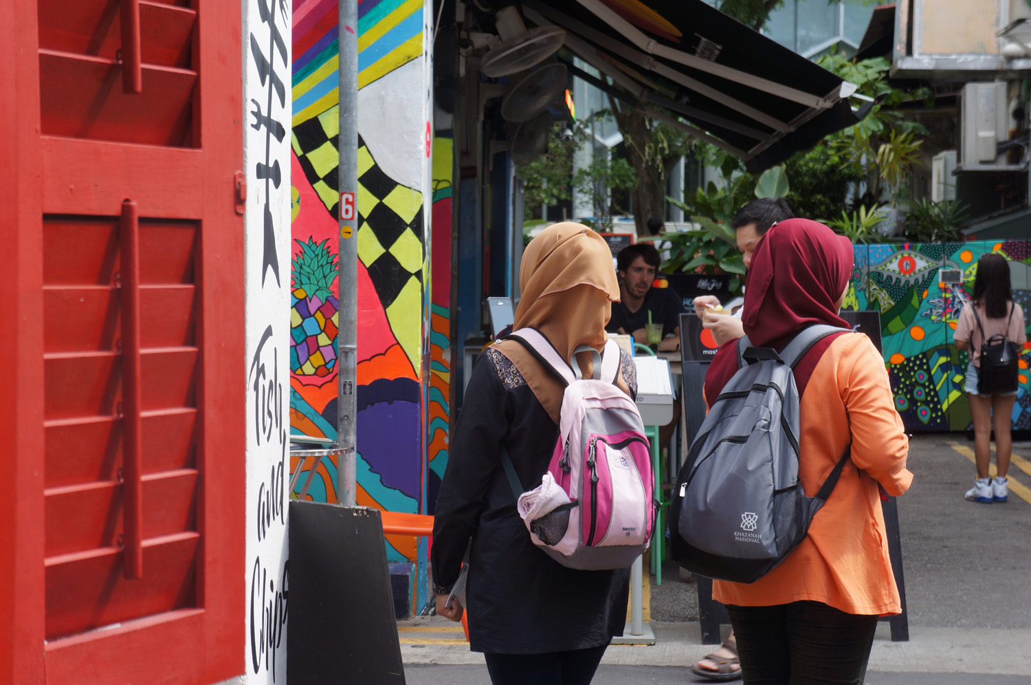 Two women walking past a colourfully painted building