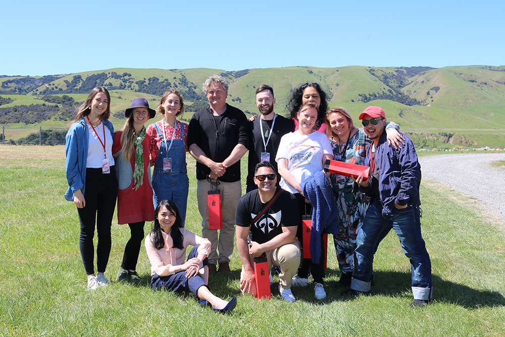 The group posing for a photo on a field with green hills behind
