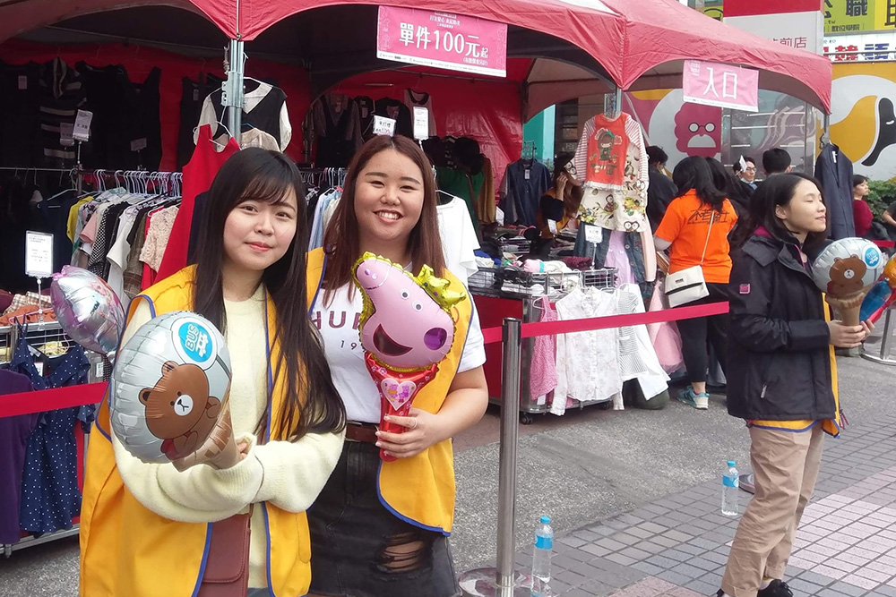 Tina with a friend holding animal balloons at a market