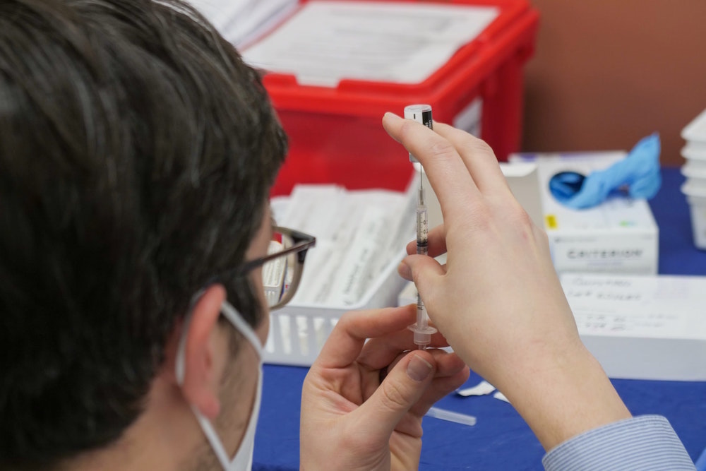 A man taking a liquid out of a syringe with a hypodermic needle
