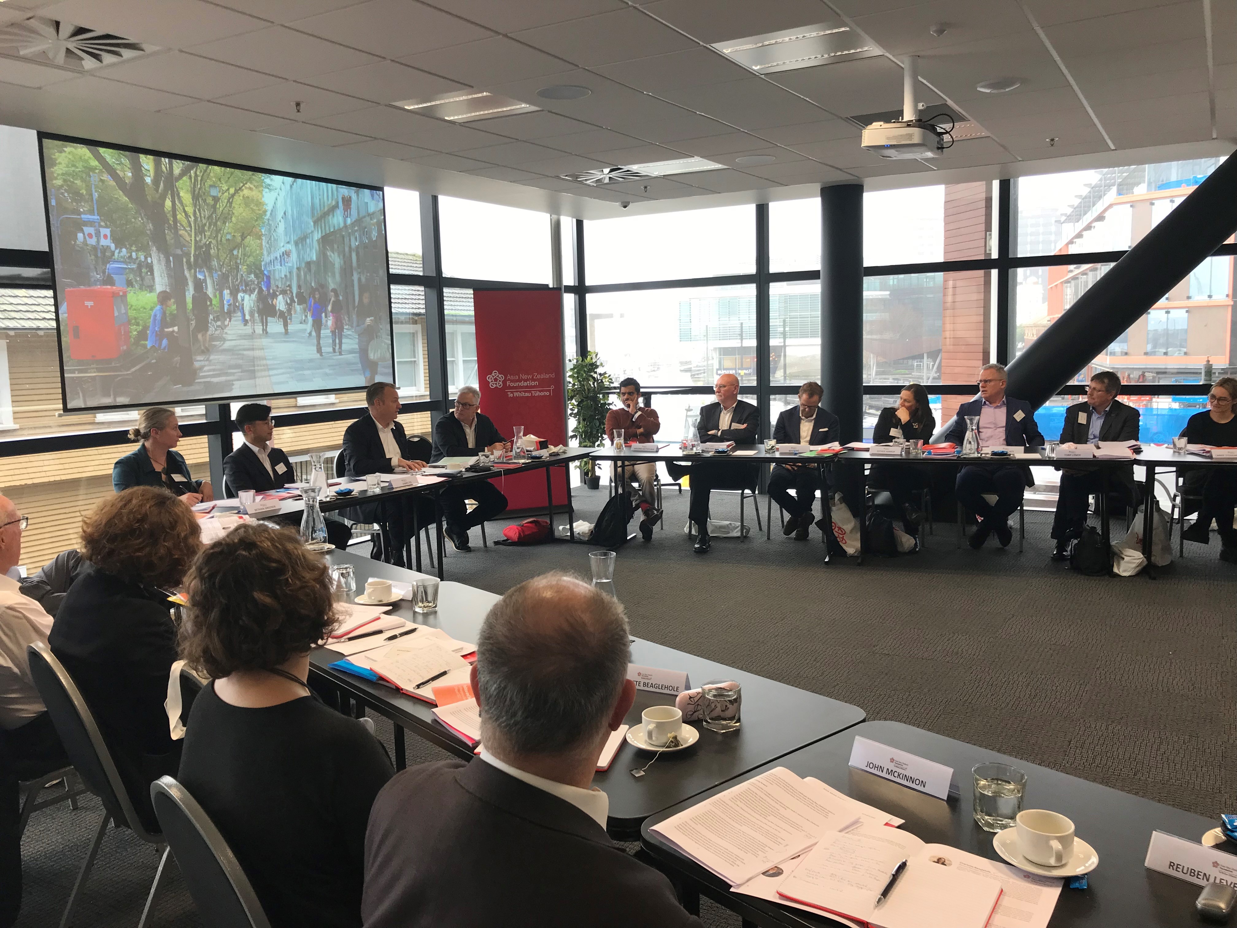 Hui participants sitting at tables around a room listening to a speaker