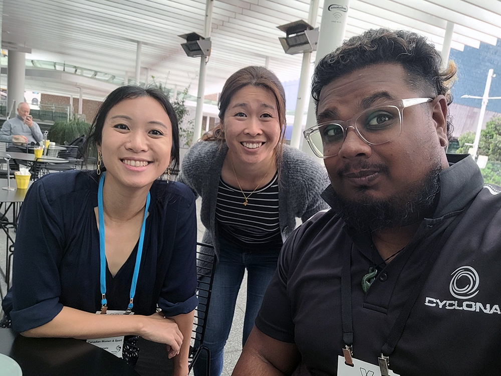 Sheryne Lok crouching between a man and a woman for a selfie
