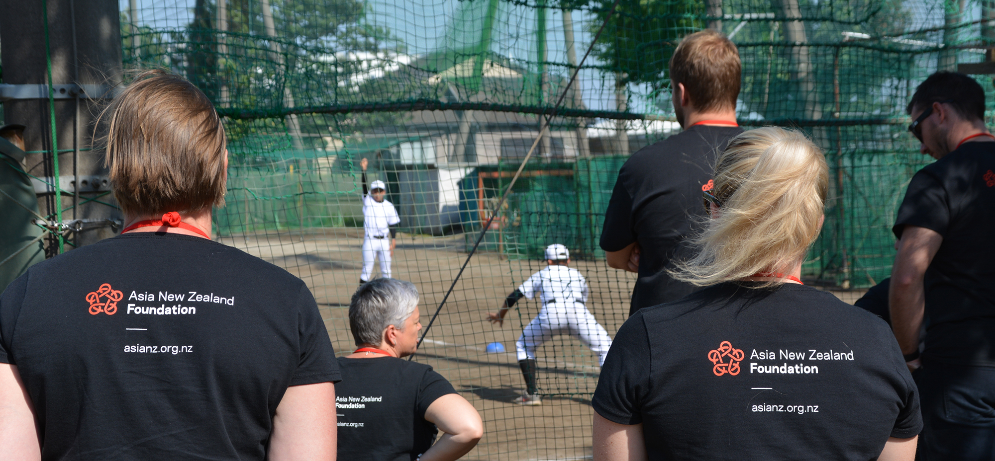 Teachers wearing Asia New Zealand Foundation t-shirts watching children play baseball in Japan