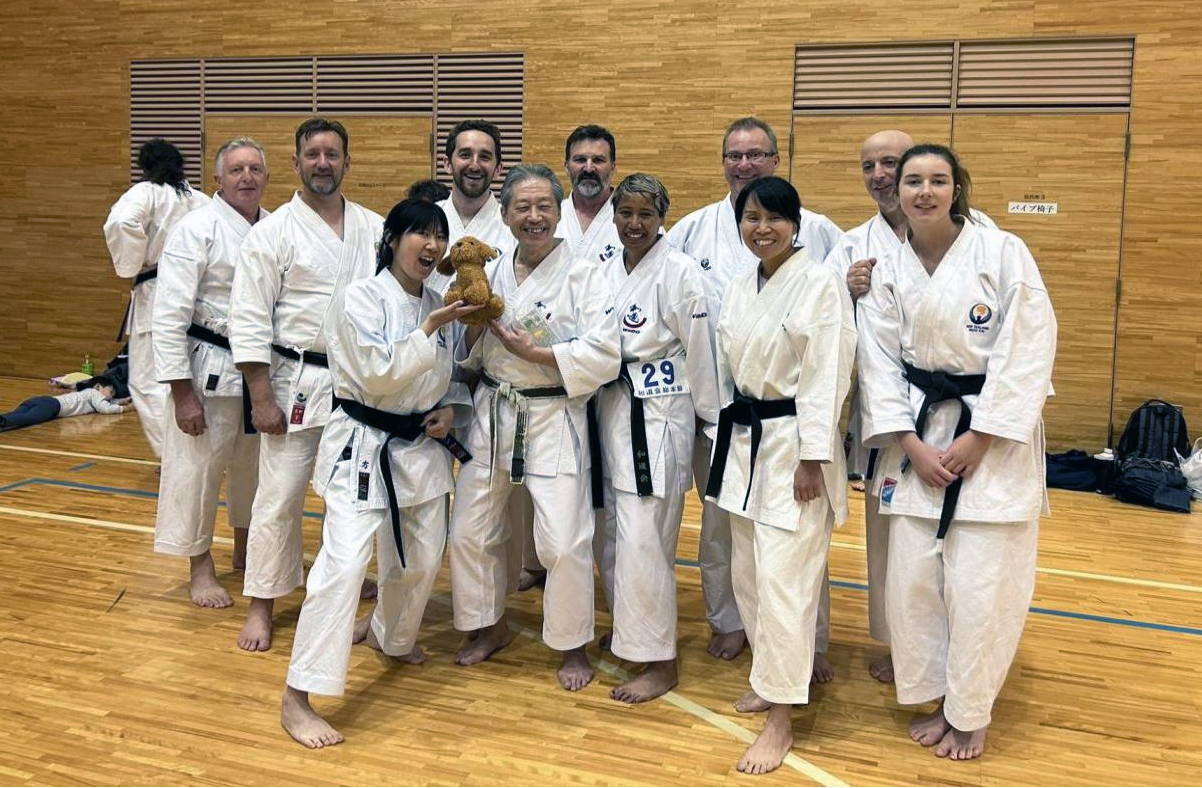 A group shot of the team in a gym in their karate uniforms