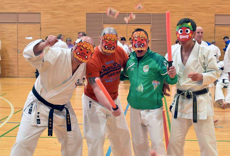 Four of the team in a gym wearing painted demon masks