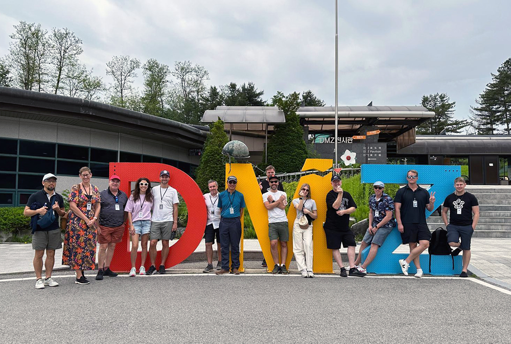 The delegation standing in front of large letters spelling out DMZ (Demiliterized Zone)