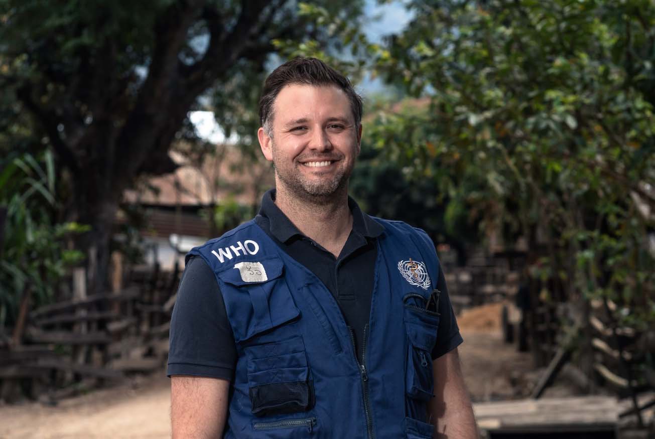 Will Seal wearing a World Health Organisation vest in a tropical place