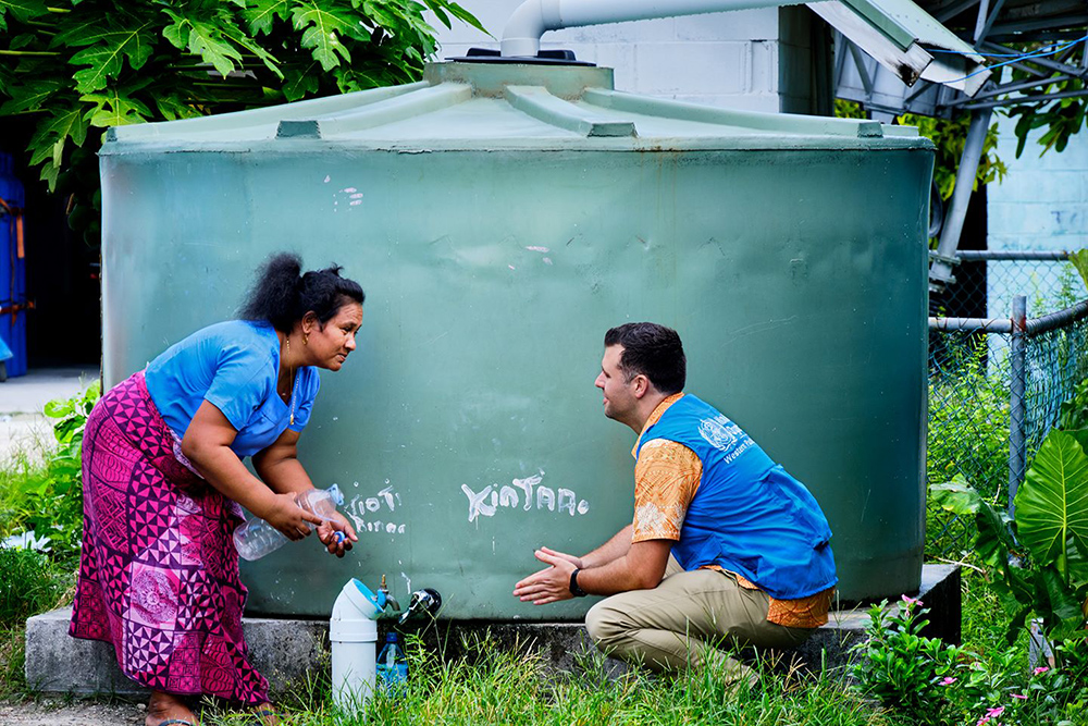 Will squatting down to talk to a woman taking water from a tank