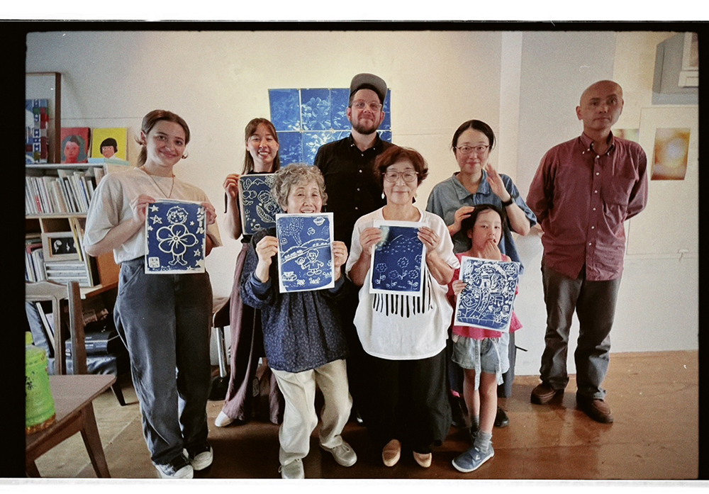 Thomas wth a group of six or seven students holding cyanotype prints
