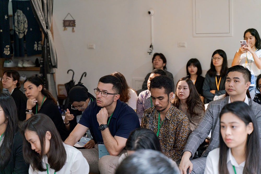 A group of young people sitting on the floor listening to a speaker