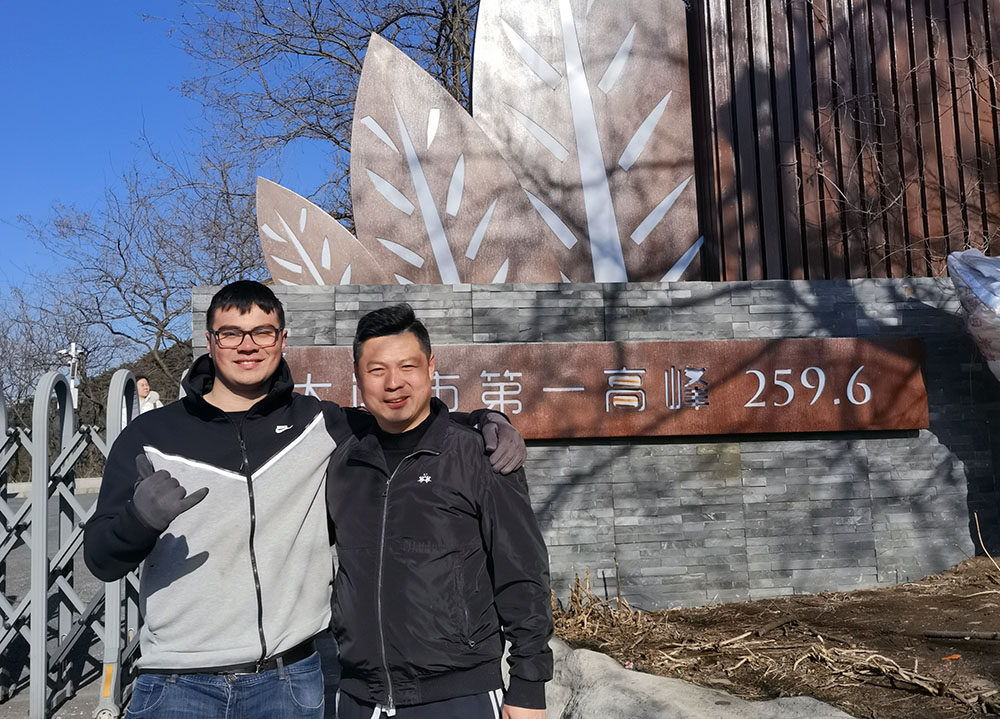 Brandon standing with his arm around a collegue in front of a public sculpture