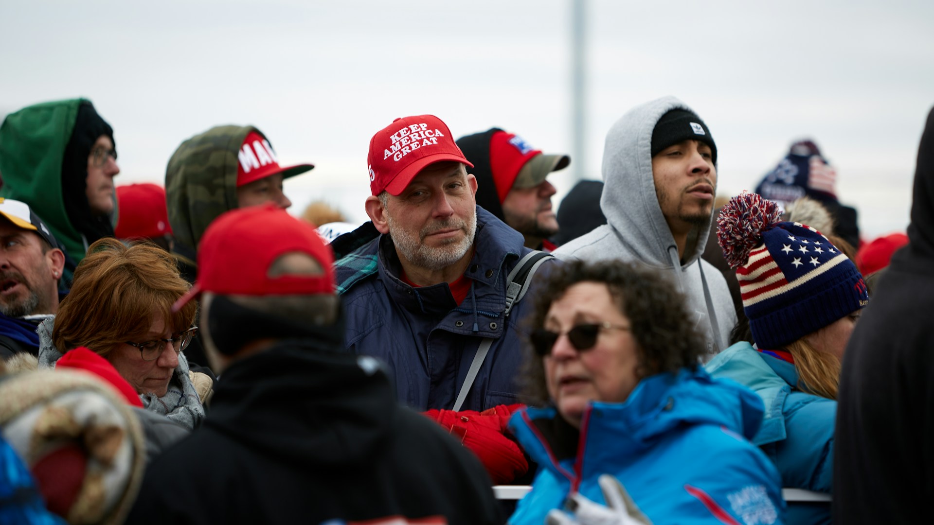 A man wearing a 'Keep America Great' cap in a crowd