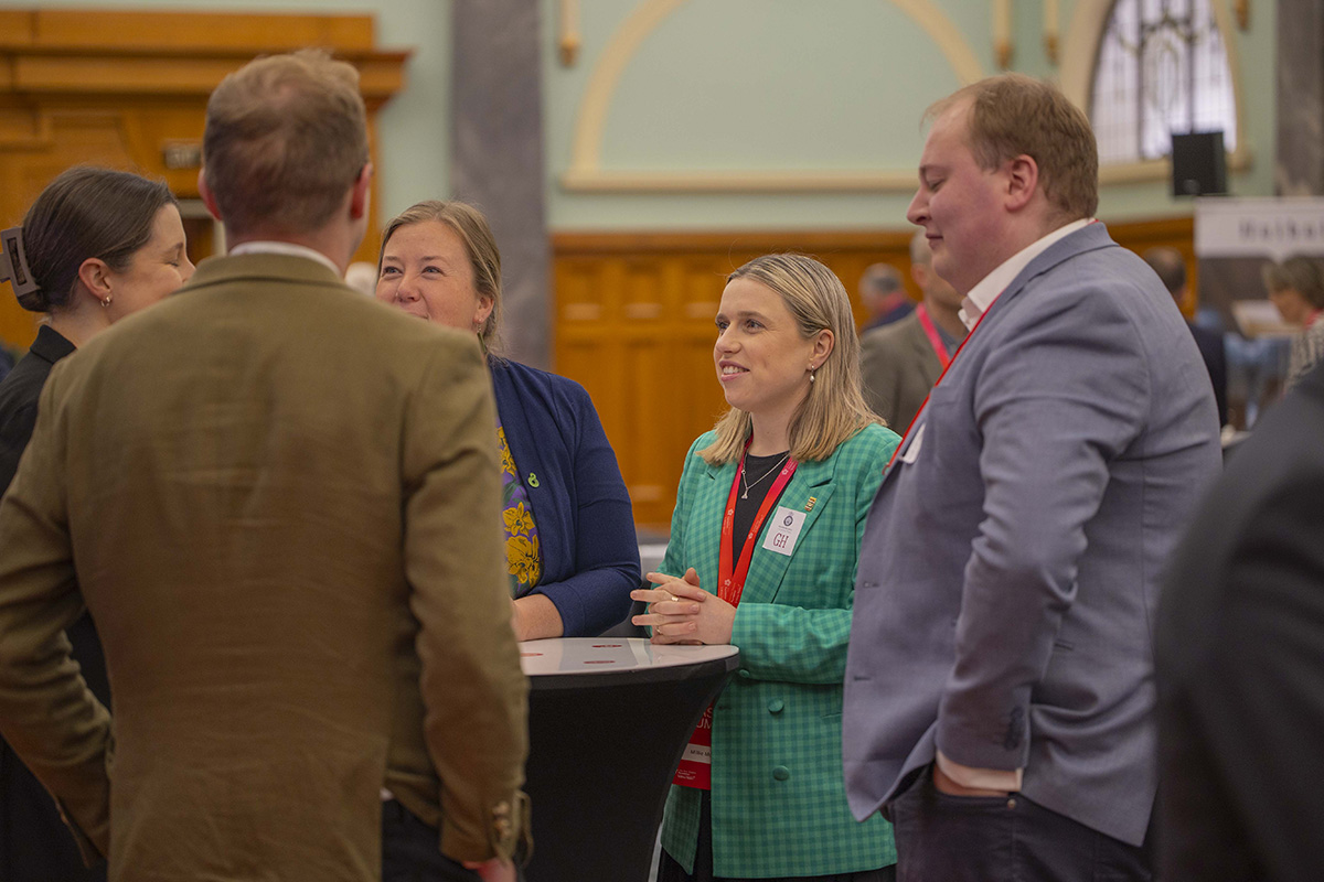 Millie standing at a table chatting with fellow Leadership Network members