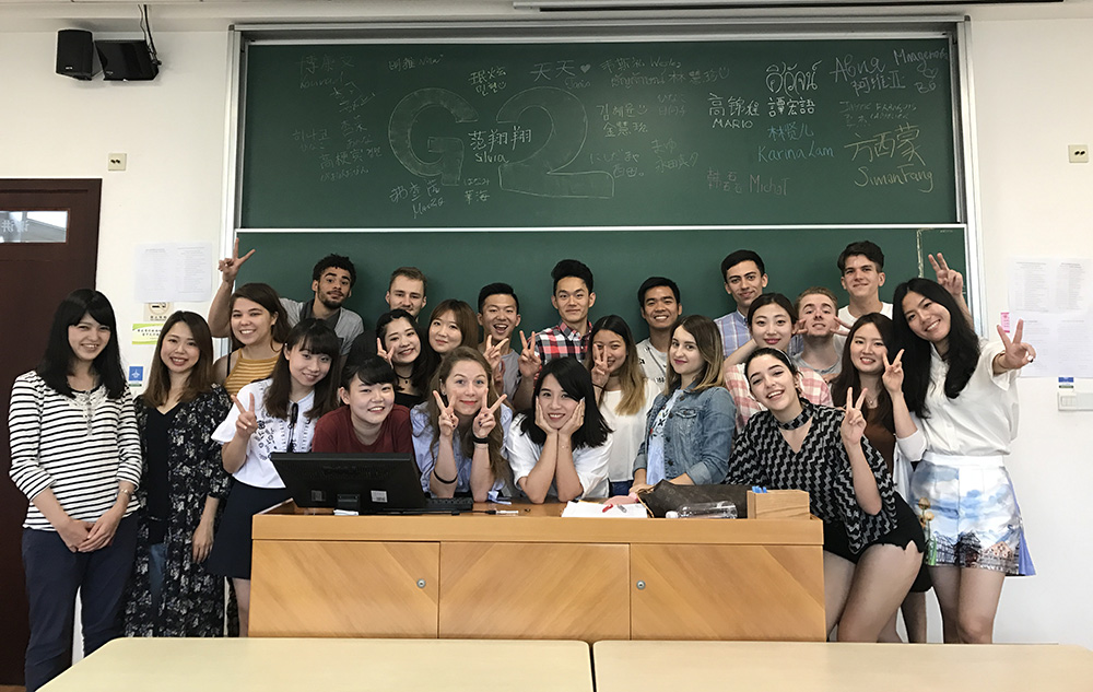 Wesley with classmates posing for a group shot in front of a blackboard