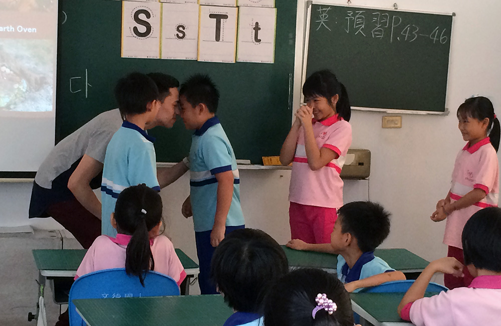 Wesley hongi(ing) a boy in a classroom
