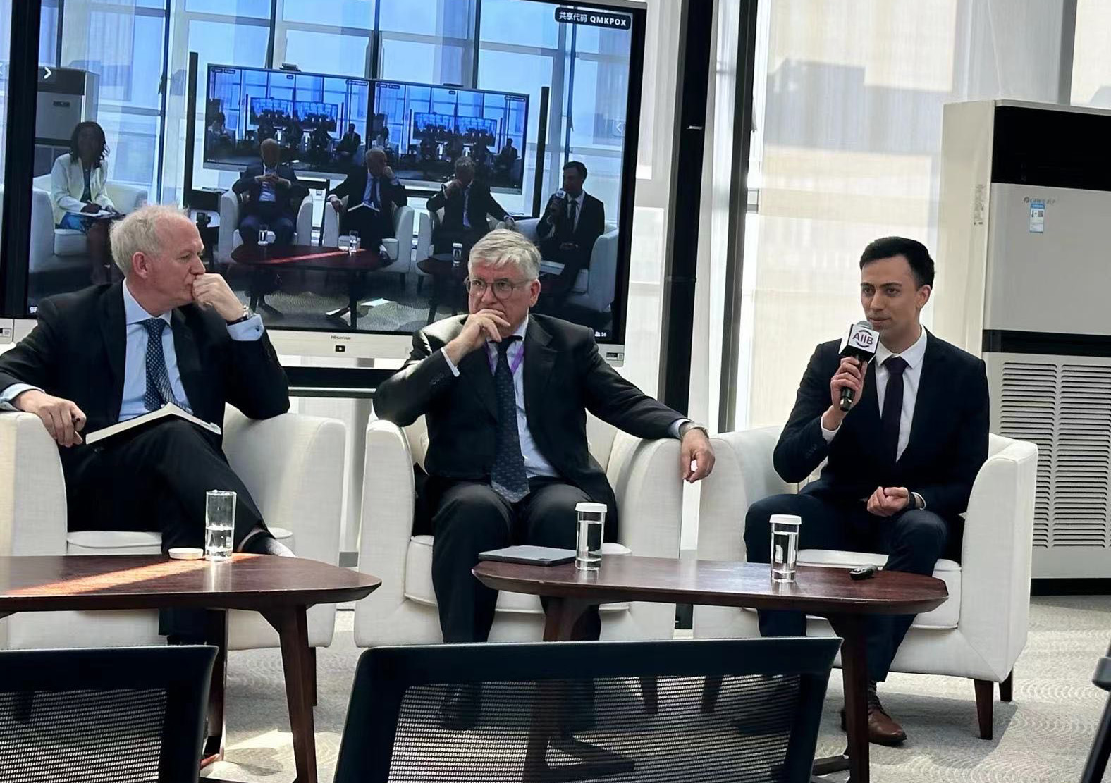 Wesley speaking into a microphone on a panel for Price waterhouse Coopers