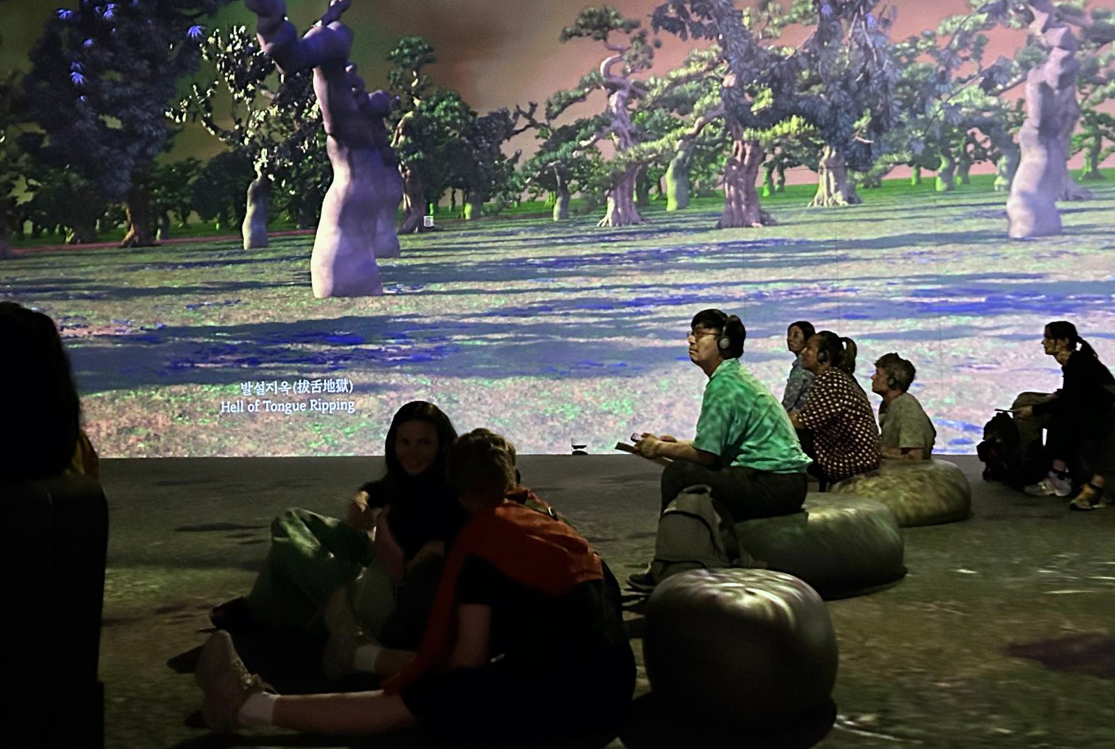 People siting in a theatre with images of trees being projected on the walls