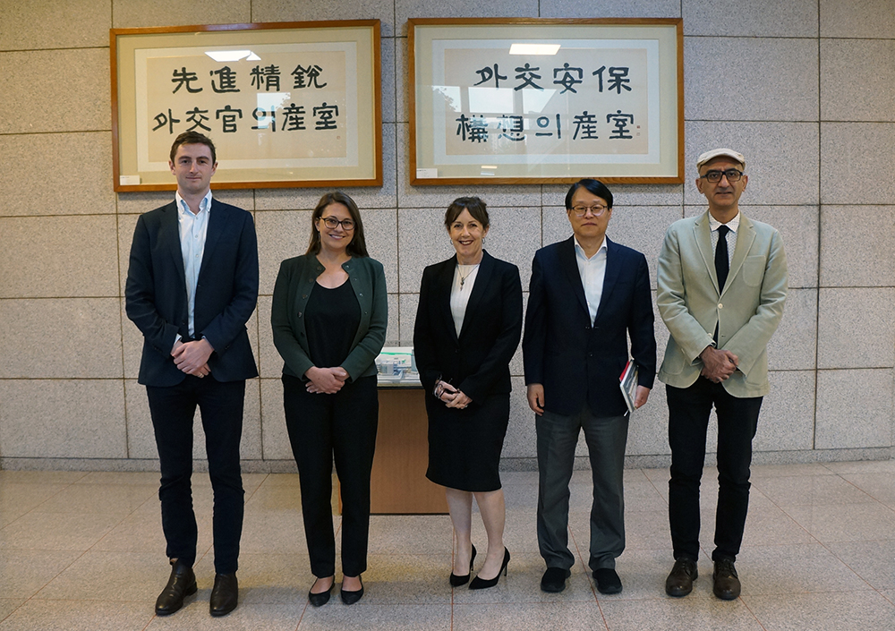 Members of the New Zealand delegation standing in front of two framed prints of Korean text