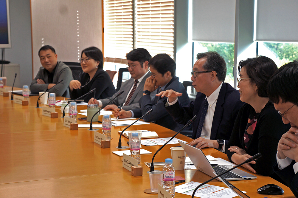 Asan institute delegation sitting at a long table in front of microphones