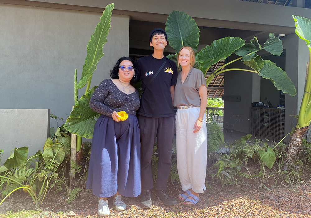 Ina with Indonesian artists Agung Prabowo and Sekar Puti standing in front of banana fronds outside ARTA DERAU, their printmaking, papermaking and ceramic studio