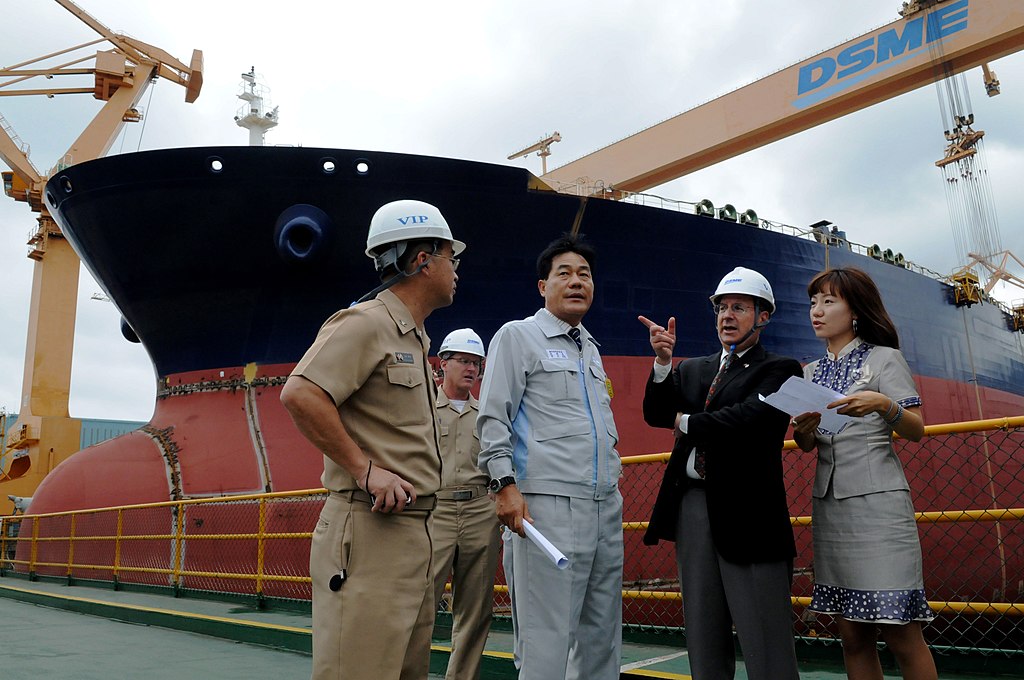 Four people talking with a large contaner ship behind them
