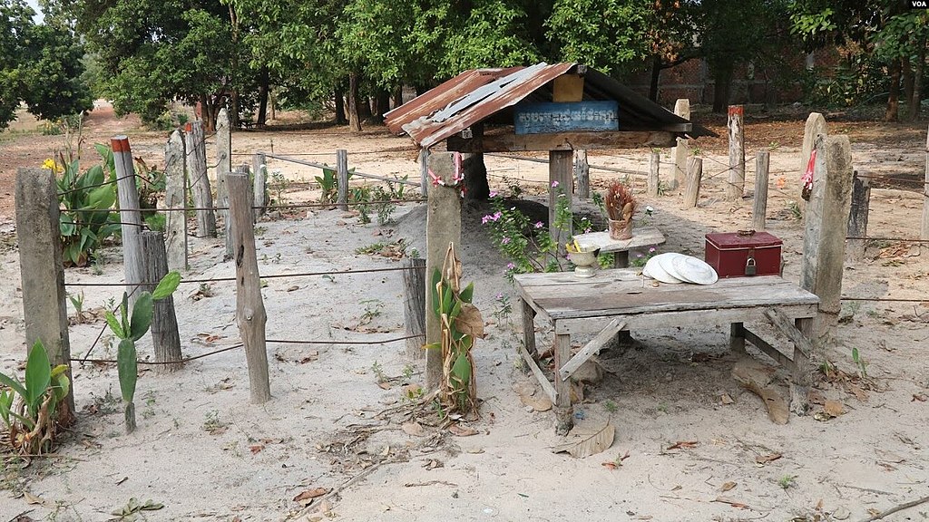 An unkempt corrugated-iron-roofed grave in a sandy plot