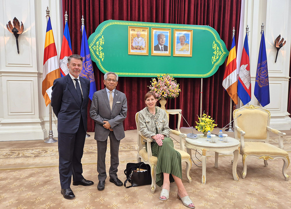 Suzannah Jessep sitting on a chair with two men standing beside her
