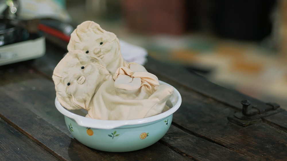 Two small figures made of cloth sitting in a bowl