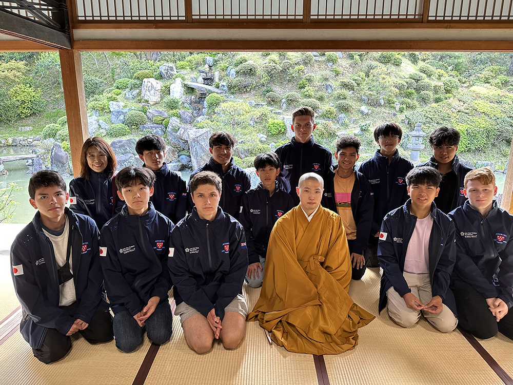 The Rosmini students sitting in a traditional Japanese building with a monk
