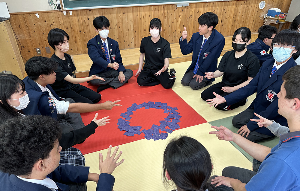 Students sitting in a circle playing hand-sign games