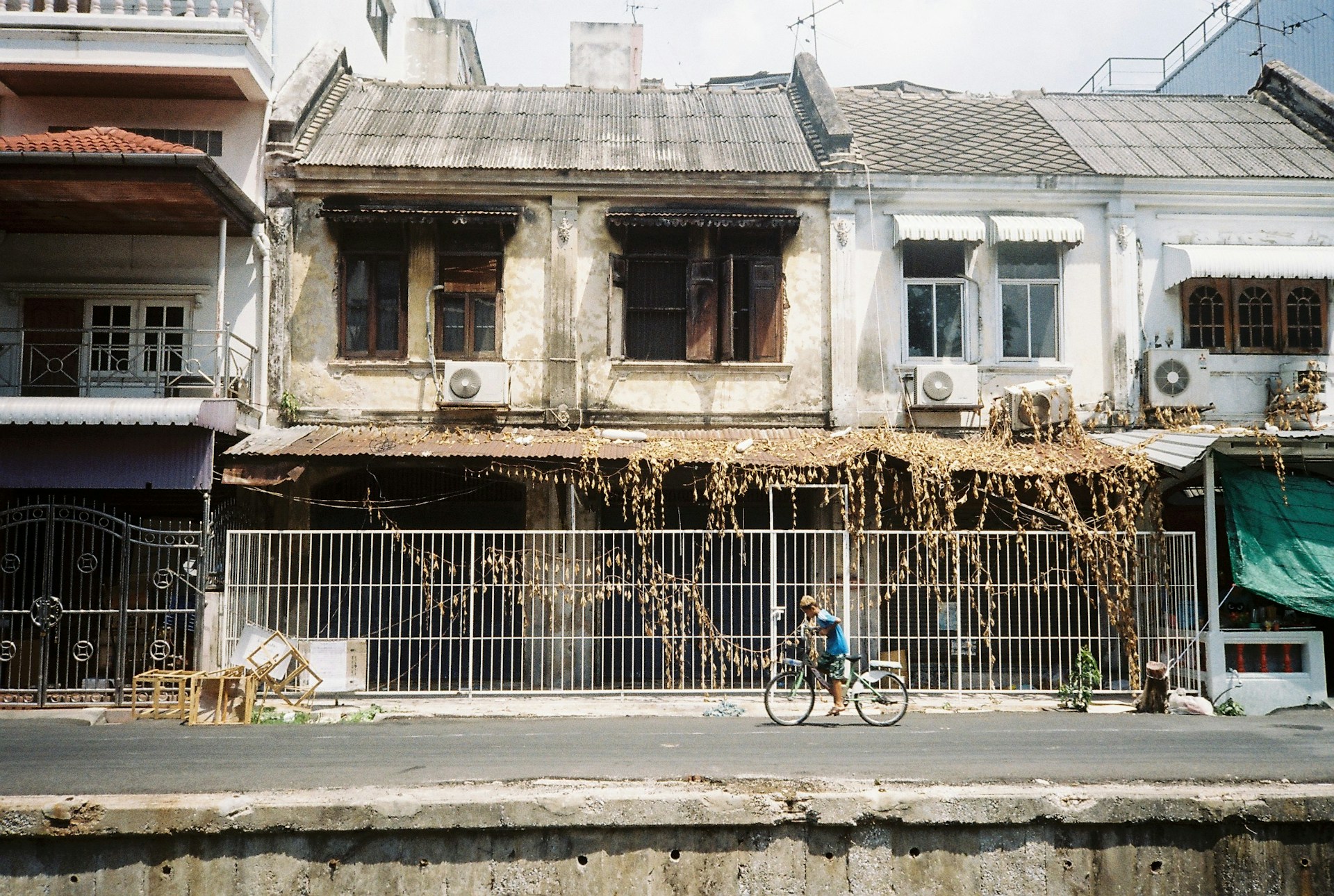 A man on a bicycle in front of derelict houses