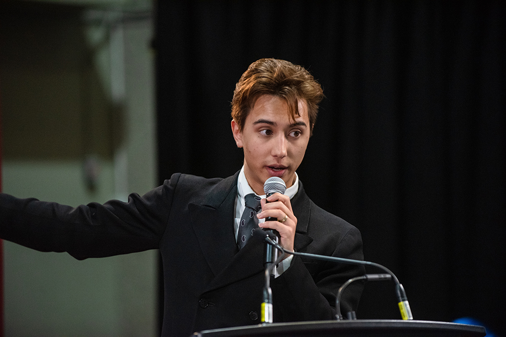 Leonardo at a podium speaking into a microphone