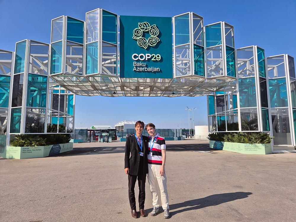 Leonardo standing with Christchurch University Students Association president Luc MacKay in front of a COP29 sign