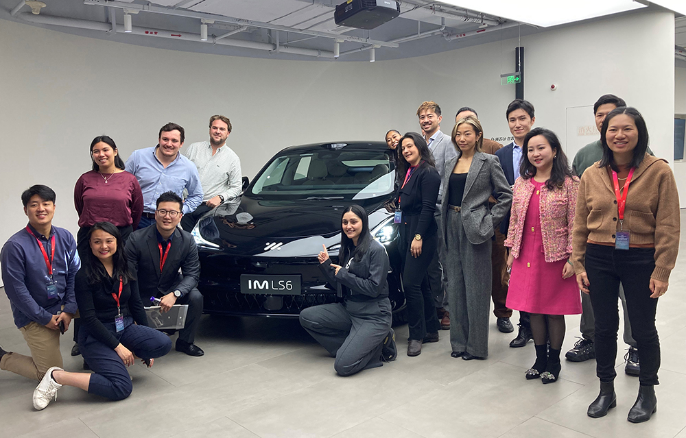 Leadership Network members gathered around an EV car in a showroom